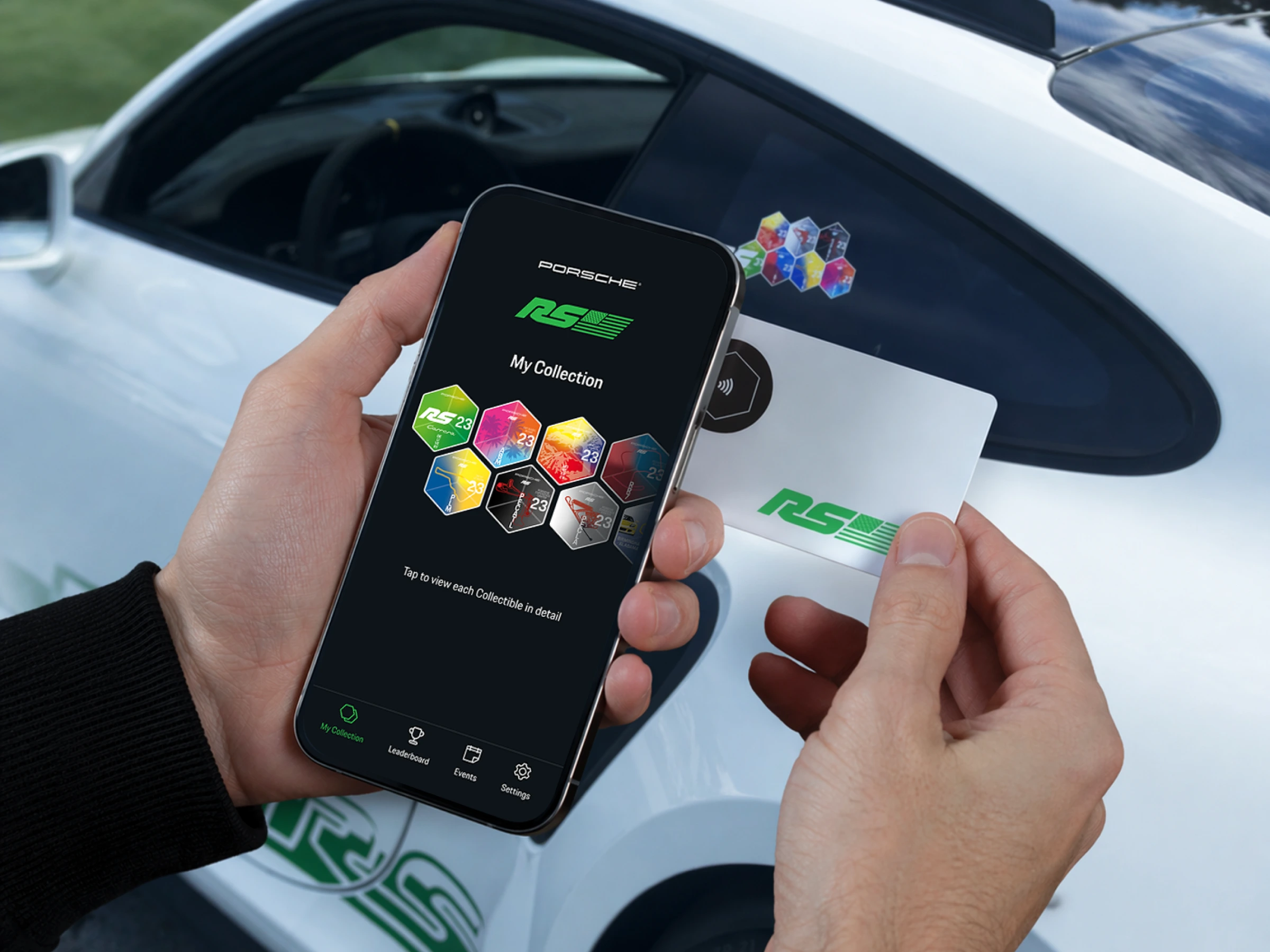 A phone showing the Porsche RS My Collection screen held beside the physical activation card, next to the GT3 RS and its hexagon collectible sticker